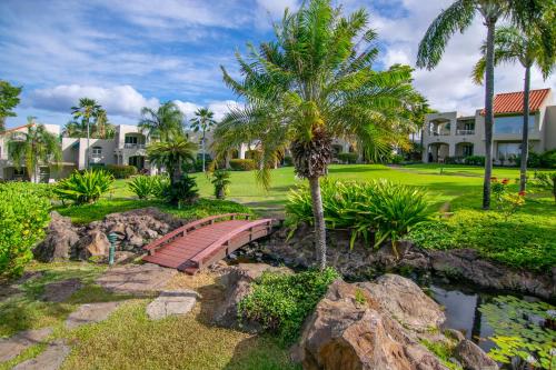 a bridge over a pond in a yard with palm trees at Palms at Wailea in Wailea