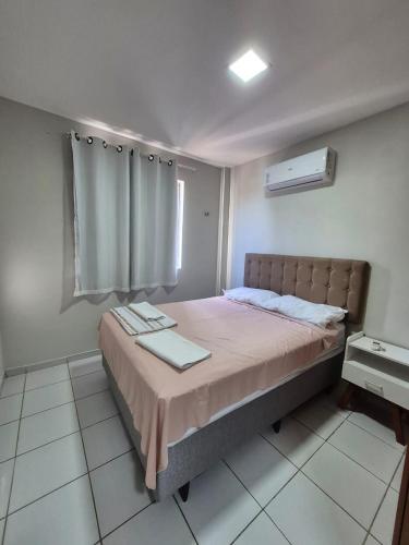 a bedroom with a large bed with a window at Em condominio in Parnamirim