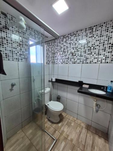 a bathroom with a toilet and a glass shower at Em condominio in Parnamirim