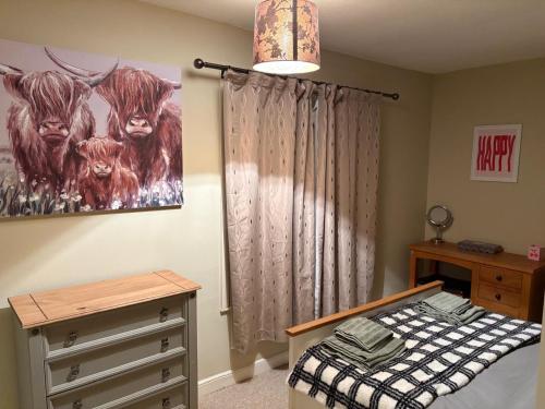 a bedroom with a bed and a painting of cows at 13 Chute Street central and homely in Exeter