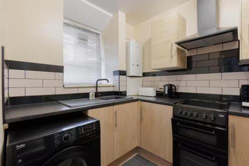a kitchen with a black dishwasher next to a sink at Cosy 2 bed in the heart of Greenwich in London