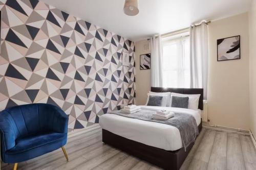 a bedroom with a bed and a blue chair at Cosy 2 bed in the heart of Greenwich in London