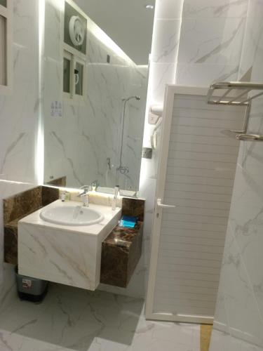 a white bathroom with a sink and a mirror at ركن فينيسيا للشقق المخدومة in Hail