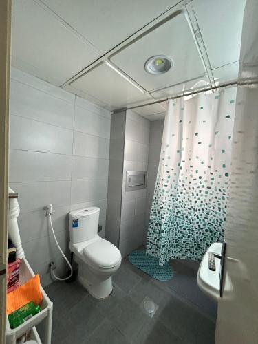 a bathroom with a toilet and a shower curtain at Vi Home Stay Corniche in Abu Dhabi