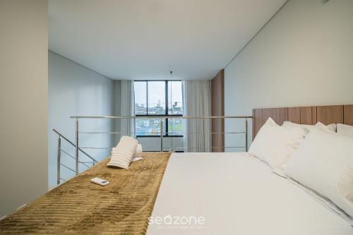 a bedroom with a large bed with a window at Full Loft 290 m from the Beach CPH0202 in Florianópolis