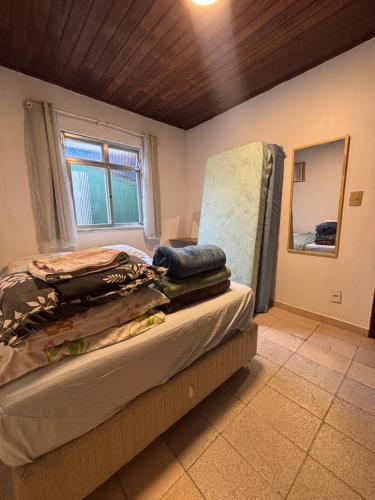 een slaapkamer met een bed met een stoel en een raam bij Casa da Gigi in Arraial do Cabo