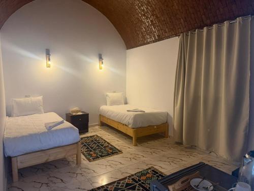 a room with two beds in a room with a window at ASKALEIH Nubian Guest House in Aswan