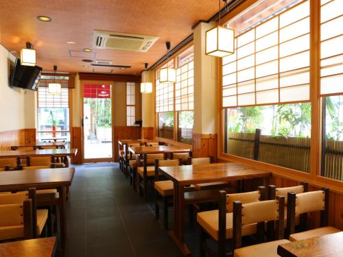 a restaurant with wooden tables and chairs and windows at Ryokan Kamogawa Asakusa in Tokyo