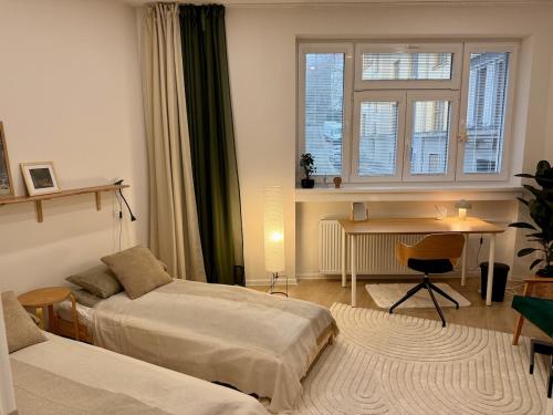 a bedroom with two beds and a desk and a window at Bratislava Cozy Corner Apartment in Vinohrady