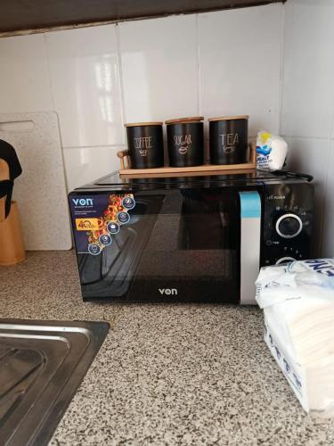 a black microwave with three coffee cups on top of it at EnkishoniBnB Kitengela in Nairobi