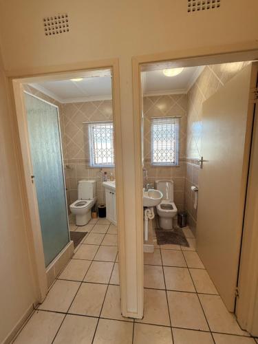 a bathroom with two toilets and a sink at Aloha Sands Scottburgh in Scottburgh
