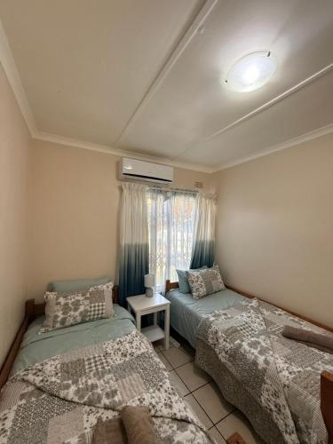 a bedroom with two beds and a window at Aloha Sands Scottburgh in Scottburgh
