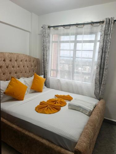 a bed with orange pillows on it with a window at EnE Homes in Kisumu