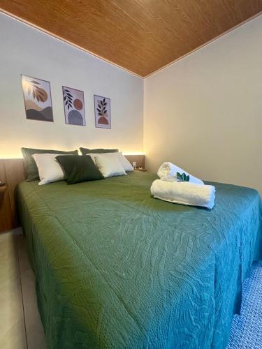 a bedroom with a bed with a green blanket at Chalés Bermond- Rota da Ferradura in Guarapari