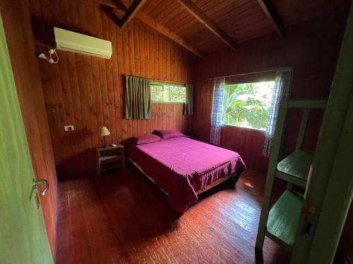 een slaapkamer met een paars bed in een houten kamer bij Nativa Iguazu in Puerto Iguazú