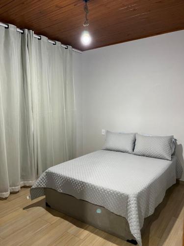 a bed in a room with white curtains at Recanto das Águas in Cunha