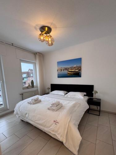 a bedroom with a large white bed with a chandelier at Ferienwohnung Allegra in Heinsberg