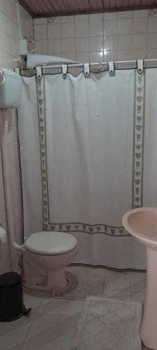 a bathroom with a shower curtain and a toilet at Casa Ximendes in São Gabriel