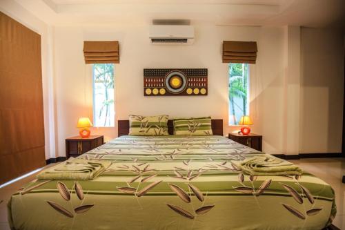 a large bed in a bedroom with two lamps at Noksawan Villa by G Estate in Rawai Beach