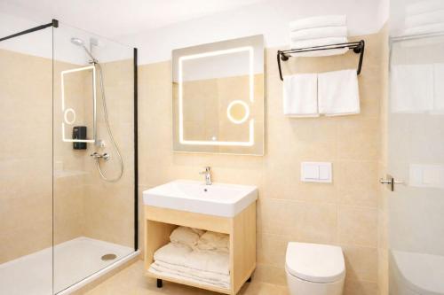 a bathroom with a sink and a shower and a toilet at Niko Hotel am Hannover Hbf in Hannover