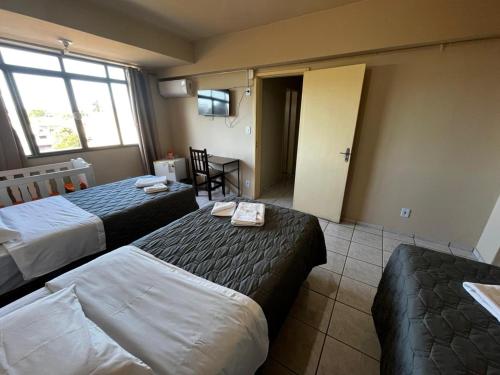 a hotel room with two beds and a table at Hotel Ermitage in Santana do Livramento