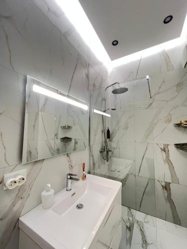 un bagno bianco con lavandino e specchio di Enrik a Tirana