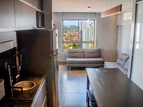 a kitchen with a refrigerator and a living room with a couch at Cobertura vista mar in Natal