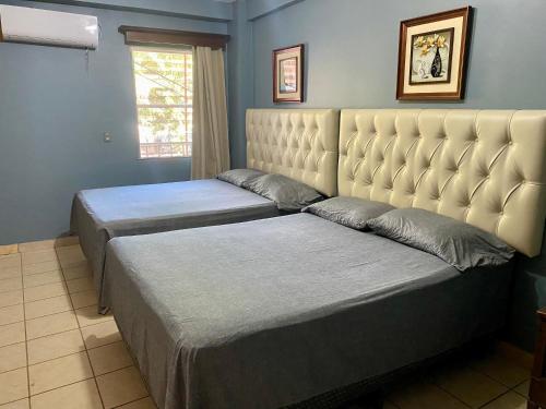 a bedroom with two beds and a large headboard at Merendon Suite Apartamento in San Pedro Sula