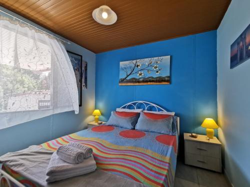 a bedroom with blue walls and a bed with red pillows at Patty's House Kallikratia in Vergia