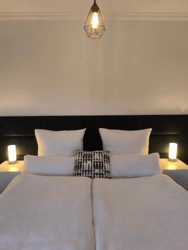 a bedroom with a bed with white sheets and two lights at Studio am Waldrand in Bad Hersfeld