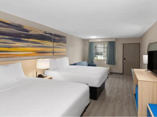 a hotel room with two beds and a flat screen tv at The Barefoot Hotel in Panama City Beach