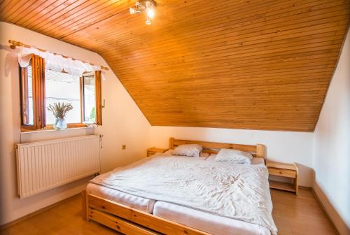 a bed in a room with a wooden ceiling at Malovaný dvůr in Dolní Dunajovice