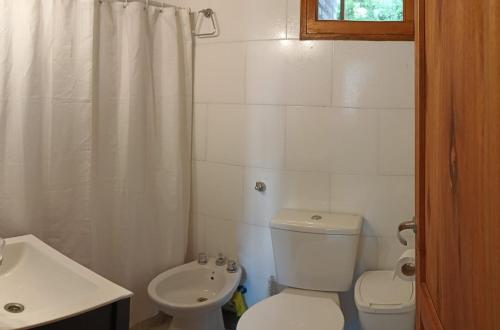 a white bathroom with a toilet and a sink at La Rubina in Villa Ventana