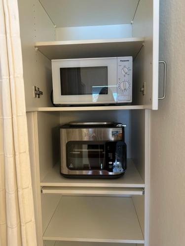 een magnetron en een broodrooster in een kast bij Ferienwohnung Kiebitzwiese in Borkum