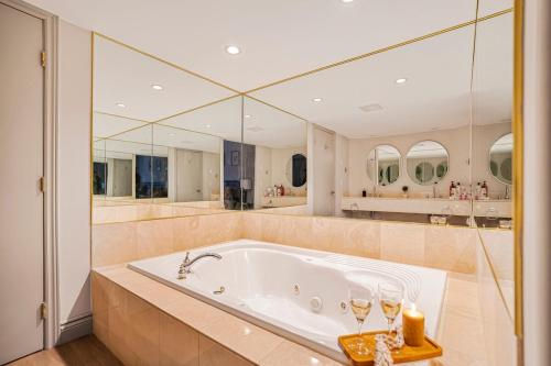a large bathroom with a tub with mirrors at Luxury Jacuzzi Suite with Sauna & Heated Pool in Shanty Bay