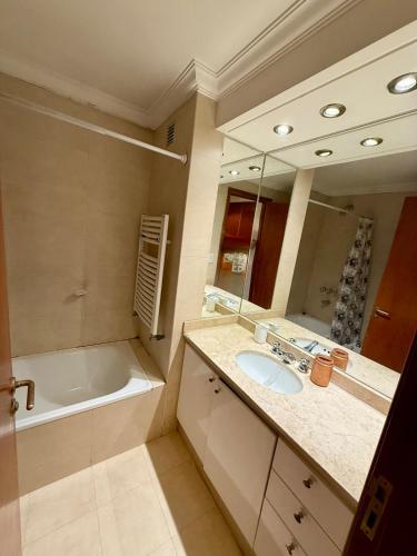 a bathroom with a sink and a tub and a mirror at Spacious Studio in Alsina in Salta
