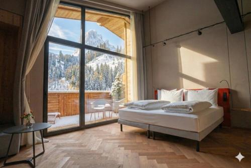 een slaapkamer met een bed en een groot raam bij La Tambra - Hotel Lodge in Santa Cristina in Val Gardena
