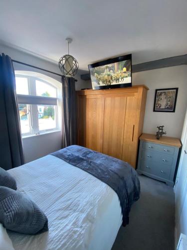 a bedroom with a bed and a tv on the wall at Comfortable Apartment set in an Old Mill in Westbury