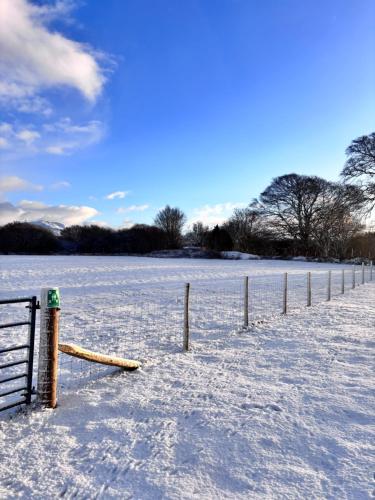een met sneeuw bedekt veld met een hek op de voorgrond bij The Pods at 7 Black Crofts in Oban