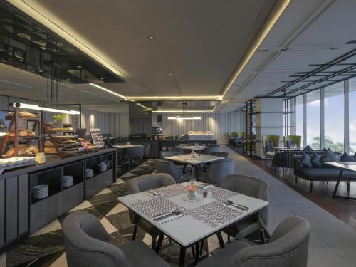 泗水Movenpick Surabaya City的一家有桌椅和窗户的餐厅