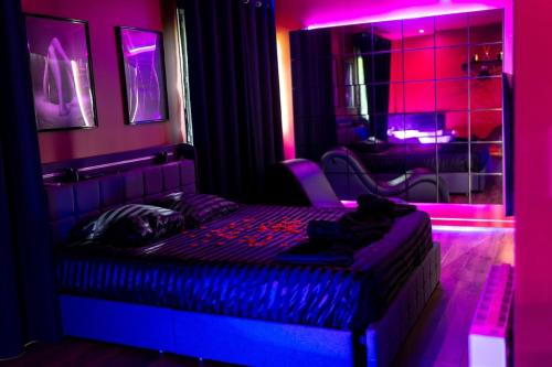 a bedroom with a bed with purple lights on it at Les secrets d hedoné in Nogna