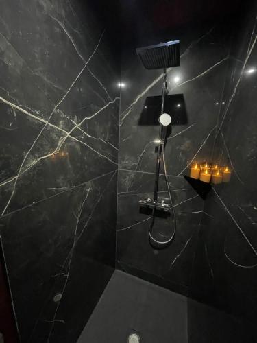 a bathroom with a shower with a black marble wall at Les secrets d hedoné in Nogna