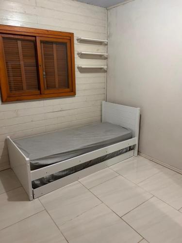 a empty bed in a room with a window at Casa com três quartos, piscina e área Gourmet in Torres
