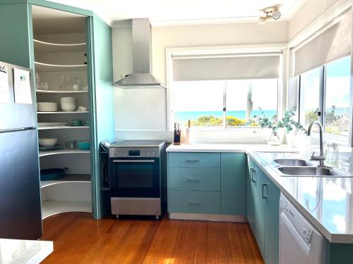 een keuken met blauwe kasten, een wastafel en een raam bij Penguin Beach House in Penguin