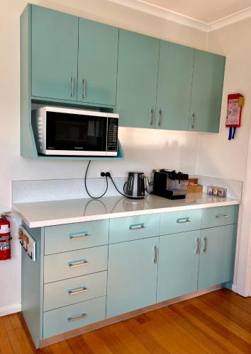 a kitchen with blue cabinets and a microwave at Penguin Beach House in Penguin