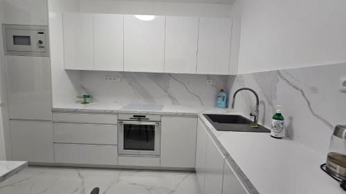 een witte keuken met witte kasten en een spoelbak bij Byt 44m2 Ostrava Bělský les in Hrabŭvka