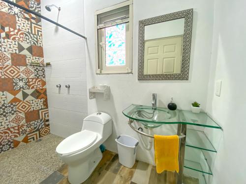 a bathroom with a toilet and a glass sink at Casa Encino con alberca climatizada en Tepoztlán in Tepoztlán