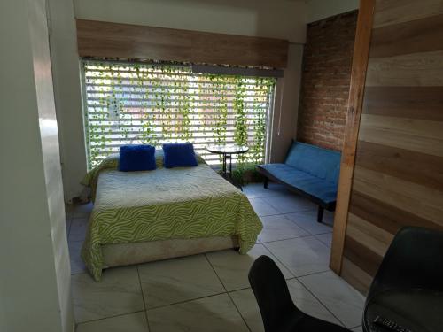 a bedroom with a bed with blue pillows and a window at HOSTEL SAKAR QUINTERO Beach in Quintero