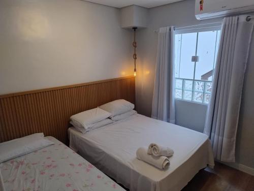 two beds in a small room with a window at Loft Juquehy in São Sebastião