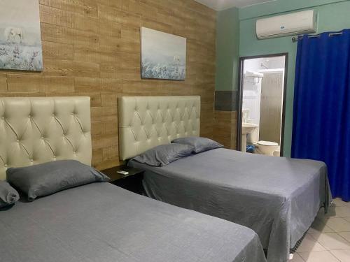 two beds in a bedroom with blue walls at Horus Suite Apartamento in San Pedro Sula